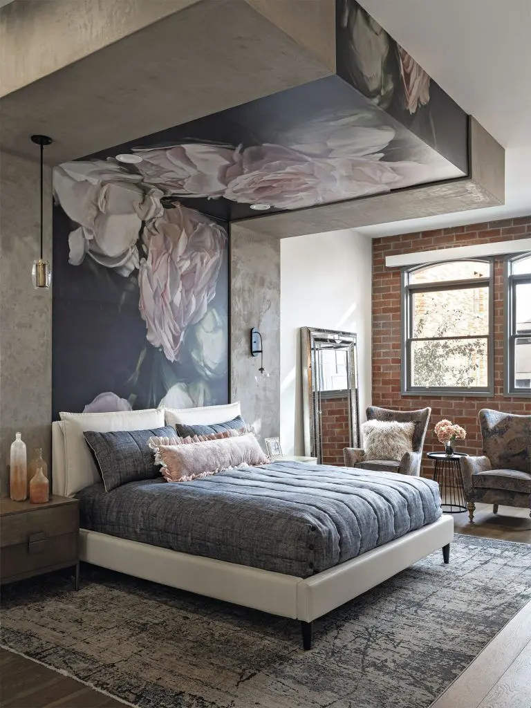 Primary bedroom: upholstered bed beneath a blush peony mural, arched windows and exposed brick